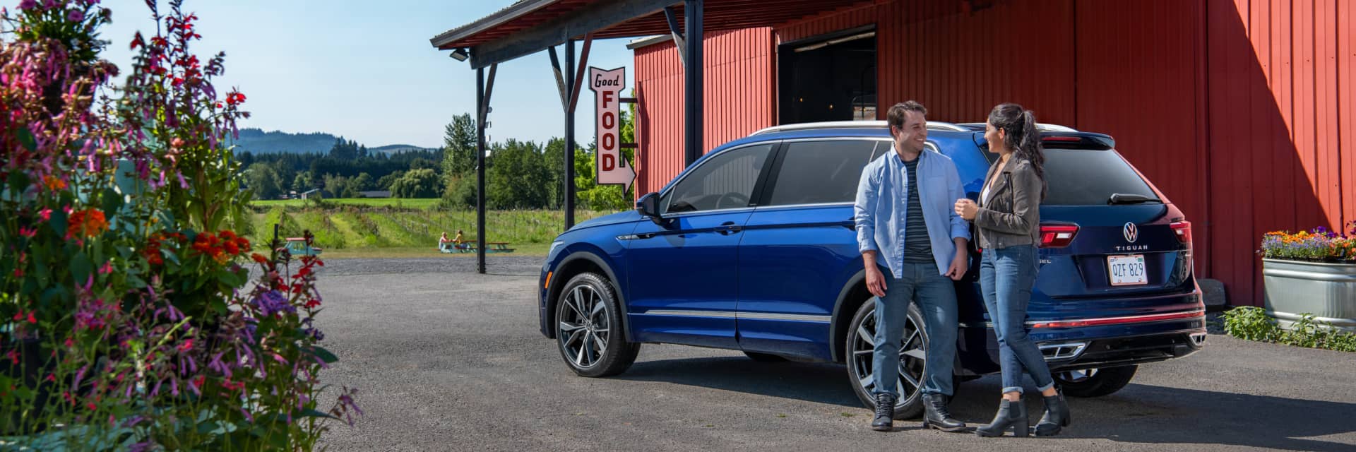 Two people outside a restaurant talking next to a blue Volkswagen SUV 